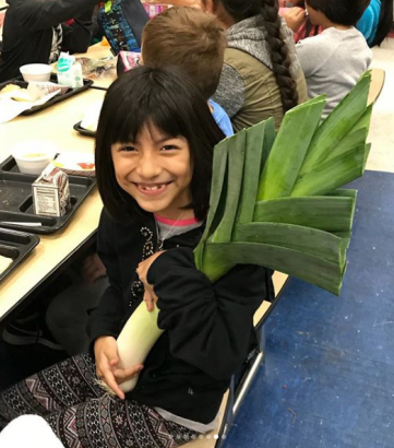 A students poses with a giant fresh leek!
